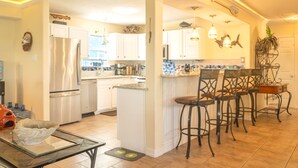 A modern kitchen with white cabinets, a central island, and bar stools.