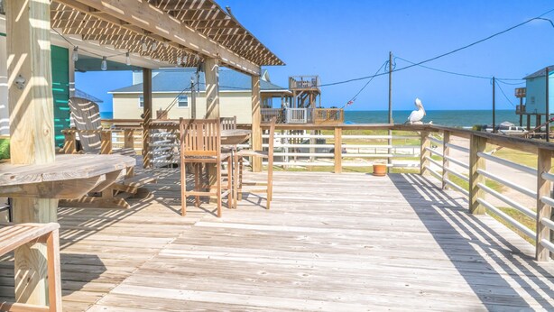 A wooden pier with picnic tables and a covered seating area overlooking the ocean.