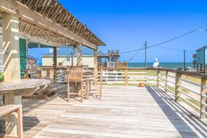 Une jetée en bois avec des tables de pique-nique et un espace de repos abrité, offrant une vue sur l’océan.
