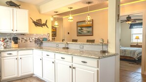A kitchen with white cabinets, a granite countertop, and pendant lighting.
