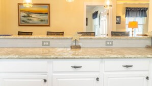A kitchen with white cabinets, a marble countertop, and pendant lighting.