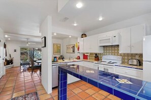 Een moderne keuken met witte kasten, een blauw betegeld eiland en een betegelde achterwand.