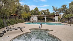 Une piscine avec un jacuzzi, des chaises longues et une structure en forme de pergola.