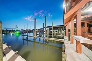 A waterfront dock with boats, a building with a covered area, and a clear sky.