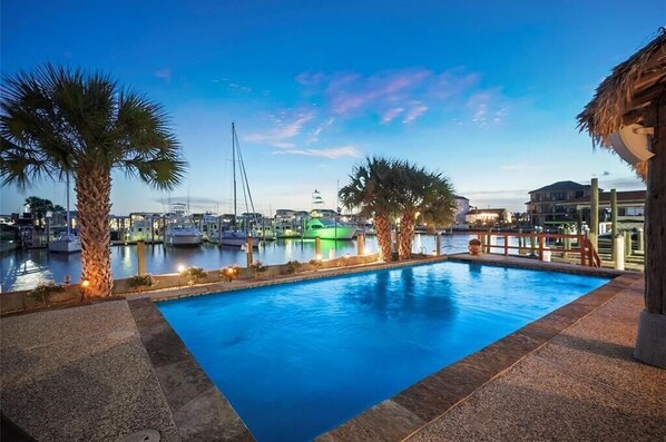 A swimming pool with a view of boats and buildings in the background.