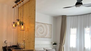 Un salon moderne avec un coin repas en bois, un lit doté d’une tête de lit et un ventilateur de plafond.