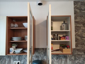 Kitchen features a cabinet with open shelves, holding kitchenware and appliances.