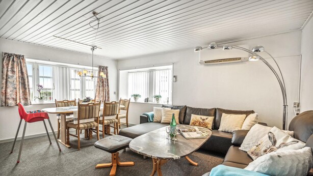 A modern living room with a dining area, a sofa, a coffee table, and a red chair.