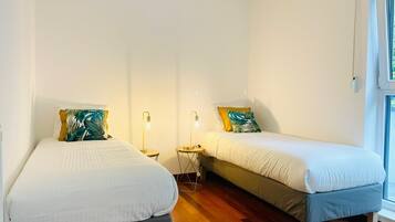Ein Schlafzimmer mit zwei Betten, einem Fenster und einem Nachttisch mit Lampe.