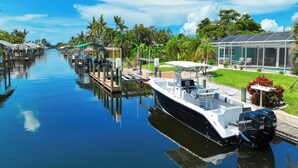 A boat docked at a marina with a covered area and a pool adjacent to it. - VRCC Villa Blue Pelican - Waterfront style & comfort (Cape Coral)
