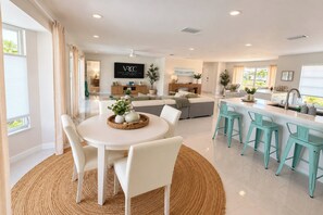 A modern kitchen with a central island, bar stools, and a dining area with a round table and chairs.