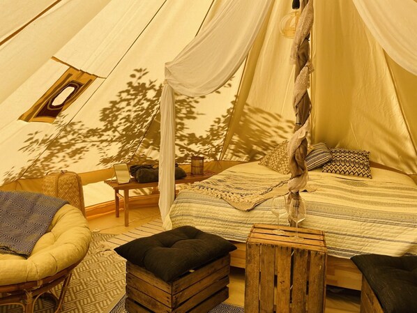Una tienda acogedora con cama, una silla, una mesita y una ventana.