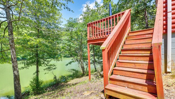 Una scala in legno conduce a un pontile con vista su un lago circondato da alberi.