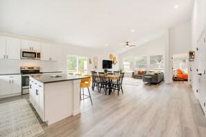 Een ruime keuken met witte kastjes, een centraal eiland en een eethoek met een ronde tafel en stoelen.