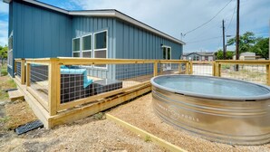 A modern building with a blue exterior, a wooden deck, and a hot tub labeled "Cowboy Pools". - Canyon Lake Oasis: Backyard & Wraparound Deck! (Canyon Lake)