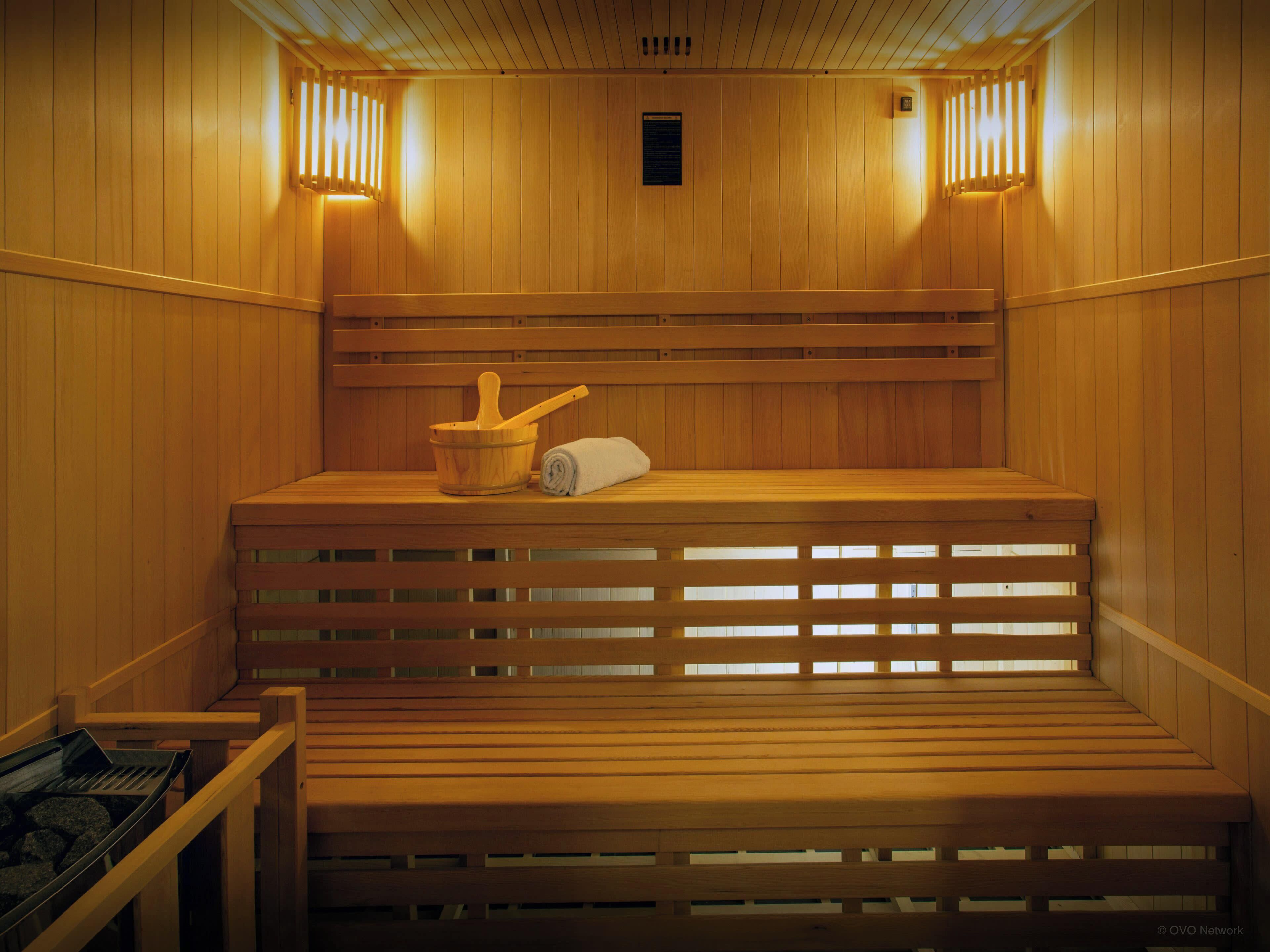 Una sauna in legno con panche, un catino di legno e un asciugamano.