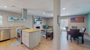 Een moderne keuken met roestvrijstalen apparatuur, een eethoek met een houten tafel en stoelen, en een woonruimte met een open haard.