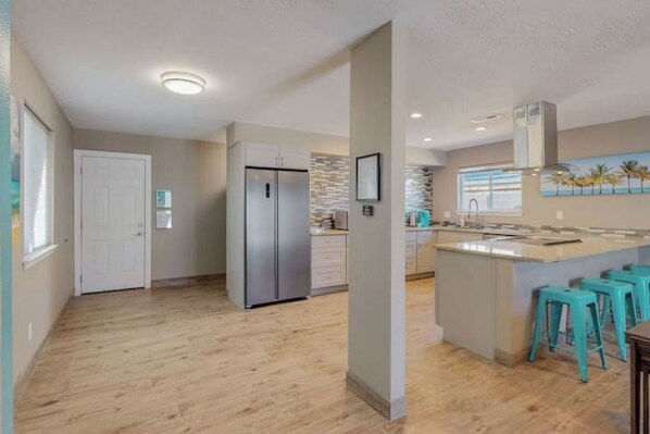 Una cocina moderna con una isla central, un refrigerador y un comedor con taburetes de bar.