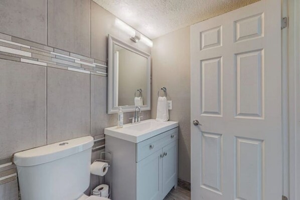 A bathroom with a toilet, sink, and mirror.