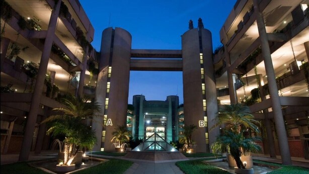 A multi-level hotel with a central atrium, outdoor lighting, and palm trees. - Cozy Studio Retreat in Zouk Mosbeh (Zouk Mosbeh)