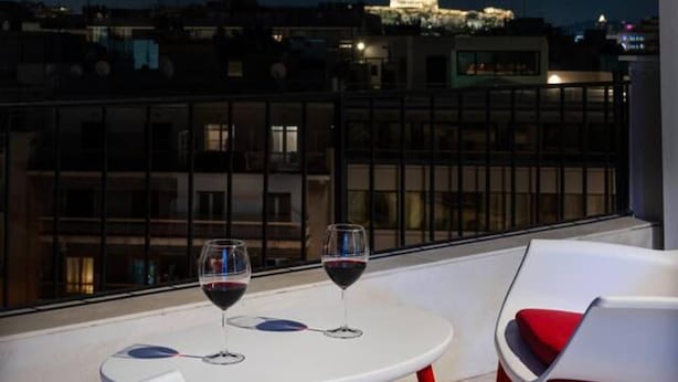 A rooftop terrace with two white tables and red chairs, overlooking a cityscape at night. - Beautiful View 8floor Loft Apartment in Athina (Athens)