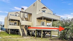 A multi-level house with a unique architectural design, featuring a prominent staircase and an overhanging structure.