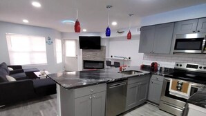 A modern kitchen with grey cabinets, stainless steel appliances, and a central island.