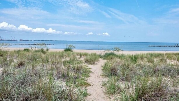 A sandy beach with a clear sky and distant water.