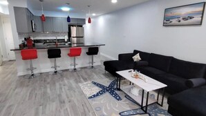 A modern living room with a black sofa, a coffee table, and a starfish-patterned rug.