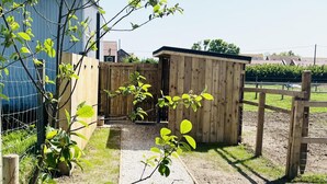 Ett trähus med en grusgång som leder fram till det, omgivet av ett trästaket och en grind av metall.