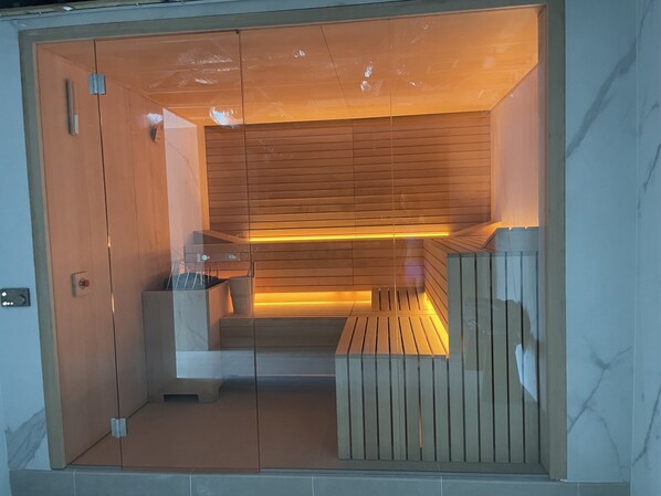 A sauna room with wooden benches, a glass door, and a wooden ceiling.