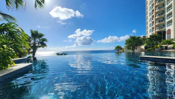 A clear view of a swimming pool with a view of the ocean and a building in the background.