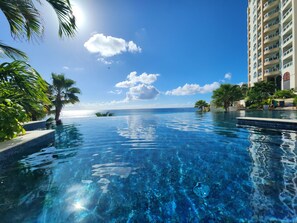 A clear view of a swimming pool with a view of the ocean and a building in the background.