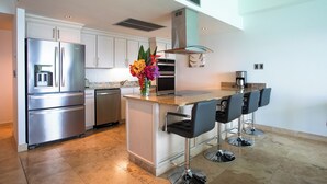 A modern kitchen with stainless steel appliances, a central island with bar stools, and a decorative flower arrangement.