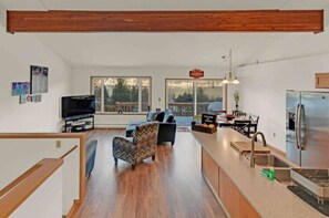 A modern kitchen with a built-in refrigerator, a dining area with a table and chairs, and a living room with a sofa and a television. - South Douglas Gem With Mountain and Ocean View Hosted By William & Melissa (Juneau)