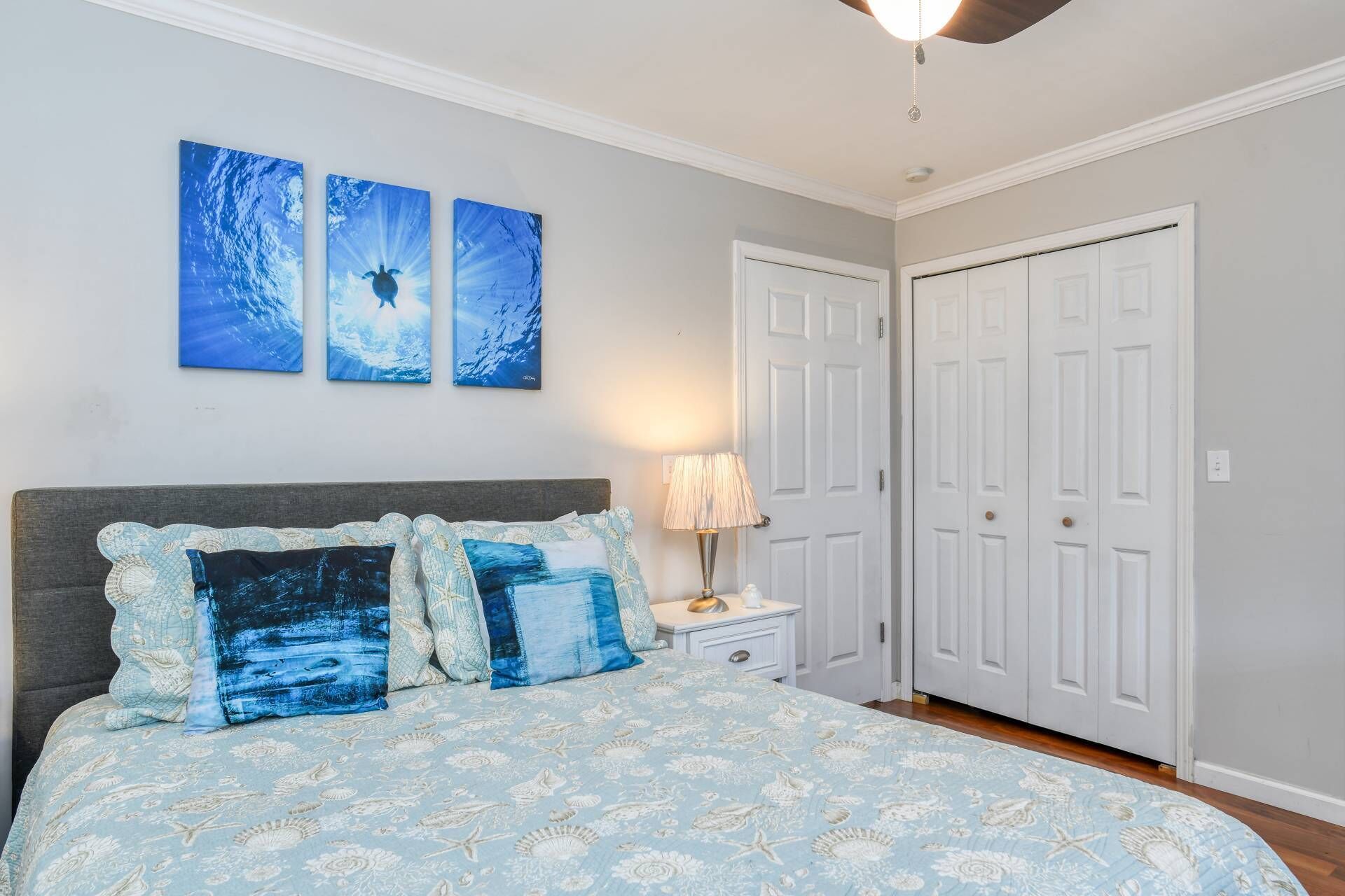 A bedroom with a bed, a nightstand, a lamp, and a closet.