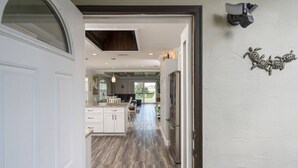A kitchen with white cabinets, a central island, and a view into the dining area. - Castillo del Sol (St. Augustine)