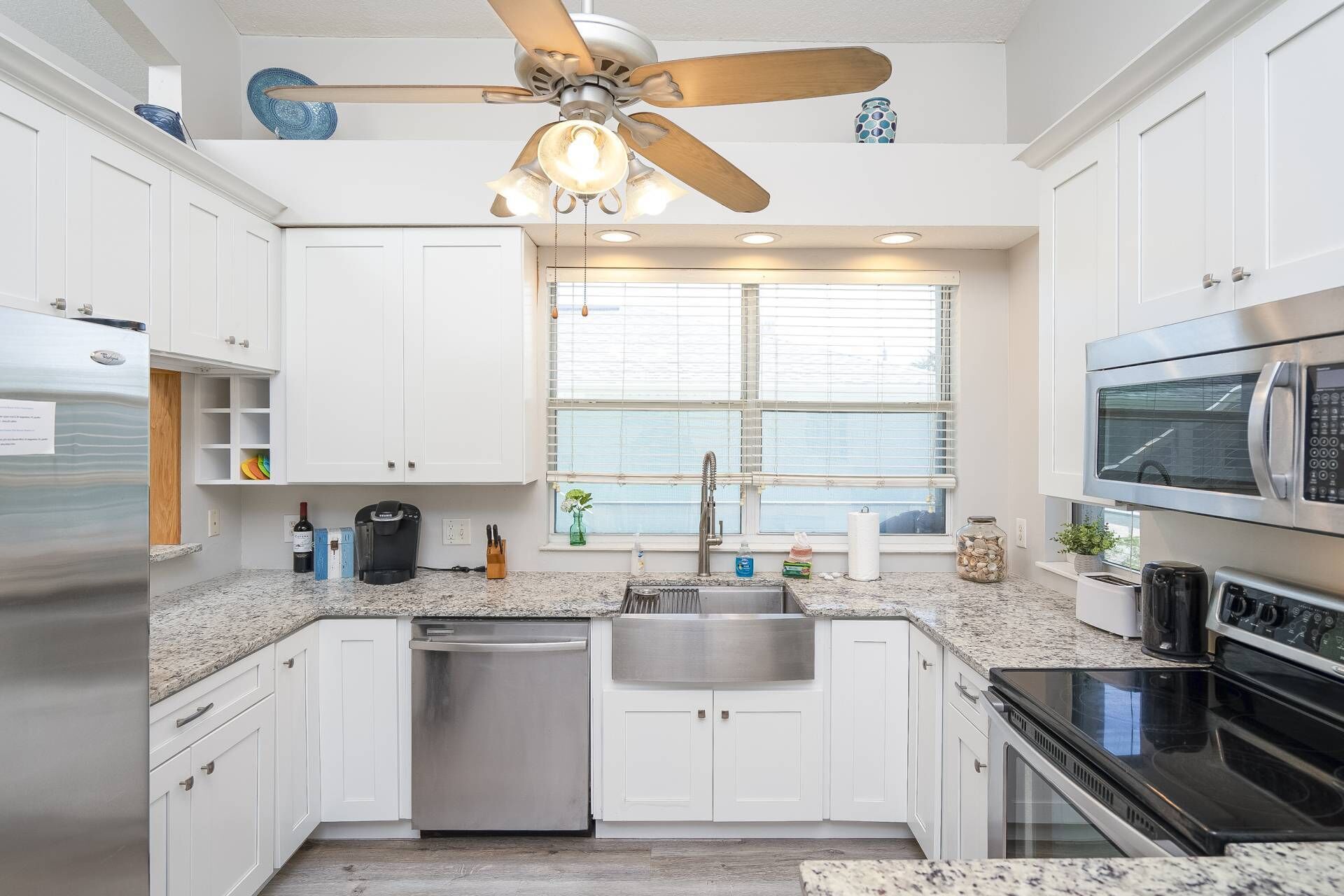 A modern kitchen with white cabinets, a stainless steel refrigerator, a dishwasher, an oven, and a microwave.