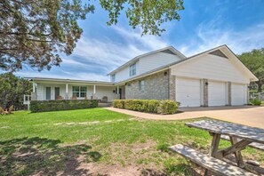 A two-story house with a covered porch, a garage, and a well-maintained lawn. - Top-rated! Gated 4-acre with game room, XL SwimSpa, Fire pit (Leander)