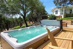 A hot tub on a wooden deck with a house in the background. - Top-rated! Gated 4-acre with game room, XL SwimSpa, Fire pit (Leander)