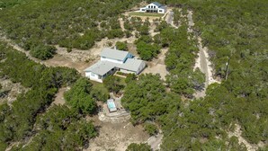 Une grande maison de plain-pied dotée d’un vaste patio et d’une piscine, le tout entouré d’une forêt dense.