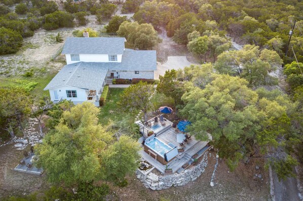 A two-story house with a large deck and a hot tub. - Top-rated! Gated 4-acre with game room, XL SwimSpa, Fire pit (Leander)
