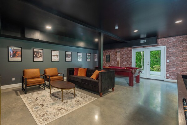 A modern lounge area with a pool table, two sofas, and framed pictures on the wall.