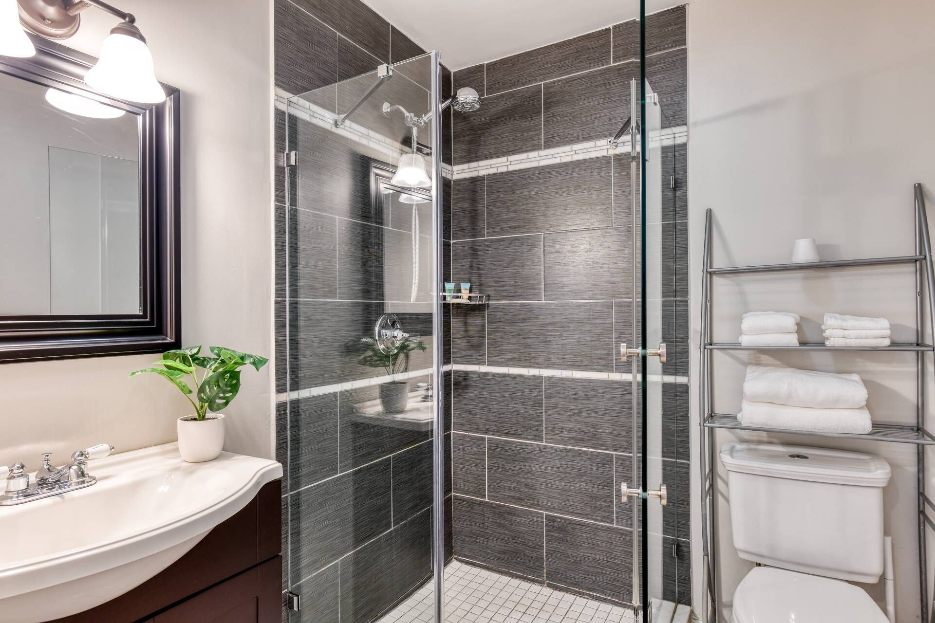A modern bathroom with a glass shower enclosure, a white sink, and a glass door showerhead.