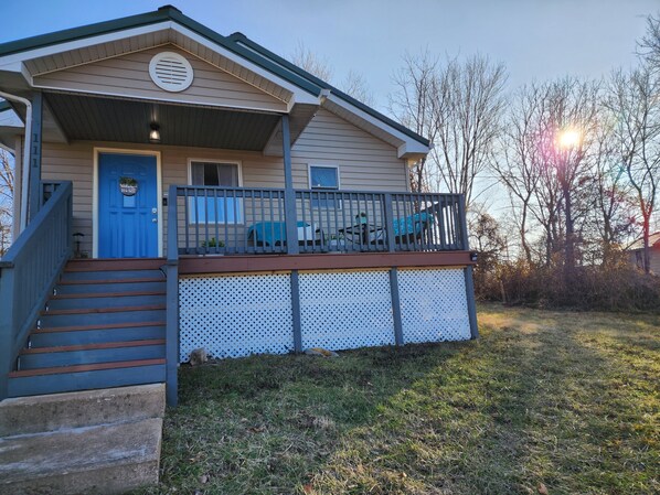 A two-story house with a blue front door, a porch with a railing, and a small deck.