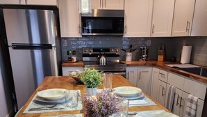 Een moderne keuken met witte kastjes, roestvrijstalen apparatuur en een houten eiland, klaar voor een maaltijd.