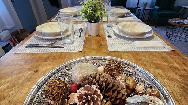 Een eettafel gedekt met borden, glazen en een decoratief middelpunt.
