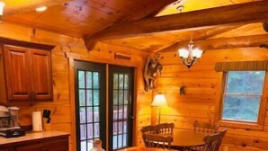 Interno di una baita in legno con un angolo bar, pavimento in legno e un tavolo da pranzo con sedie.