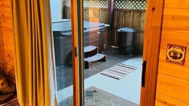 Una baita di legno con una porta scorrevole in vetro che si apre su un patio esterno con tavolo e sedie.