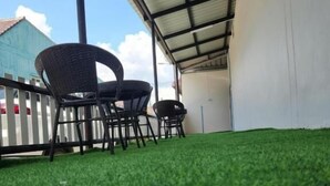A covered outdoor area with artificial grass, a white wall, and a metal roof structure. - Jipu Homestay Ai Yoe Boe Chang (Betong)